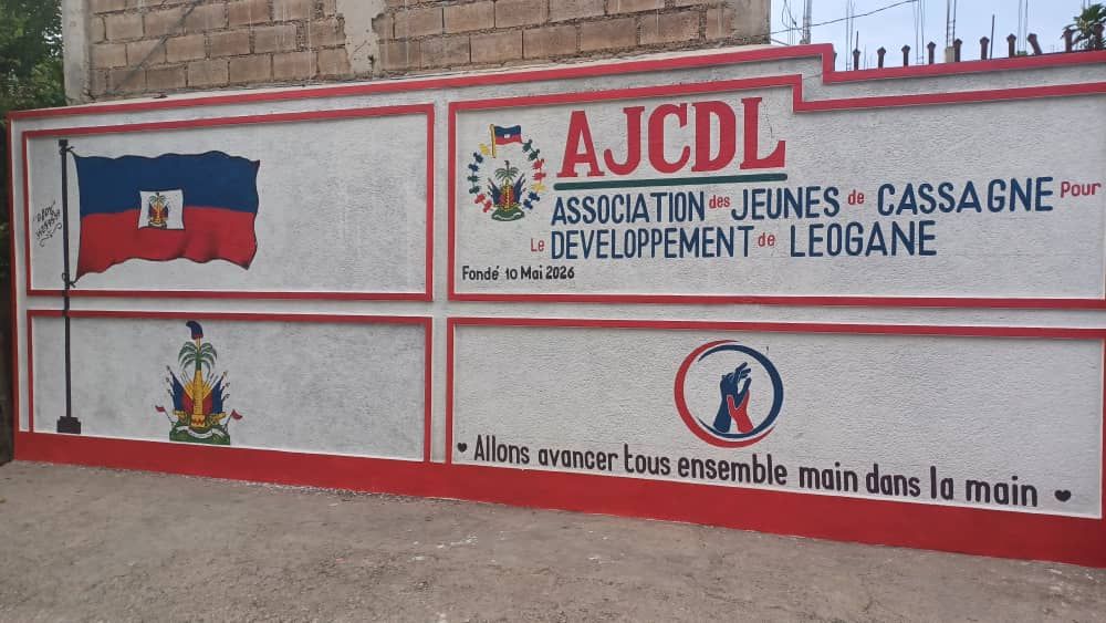 Mur peint de l'association à Cassagne, avec le drapeau et les armoiries d'Haïti et la devise « Allons avancer tous ensemble main dans la main »