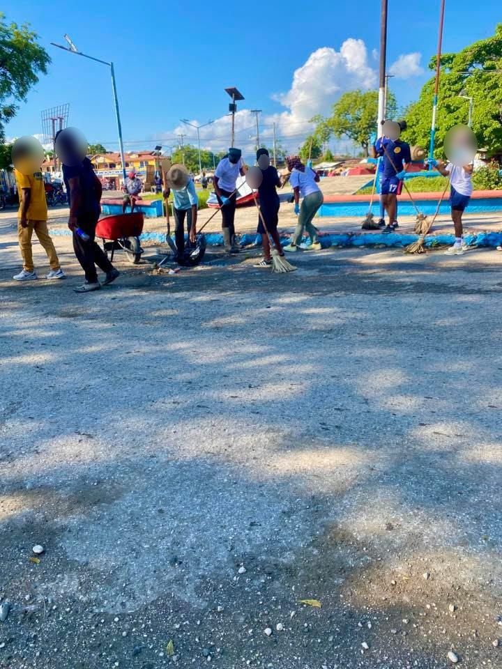 Brigade de jeunes balayant la place publique de Cassagne, brouette et balais en main