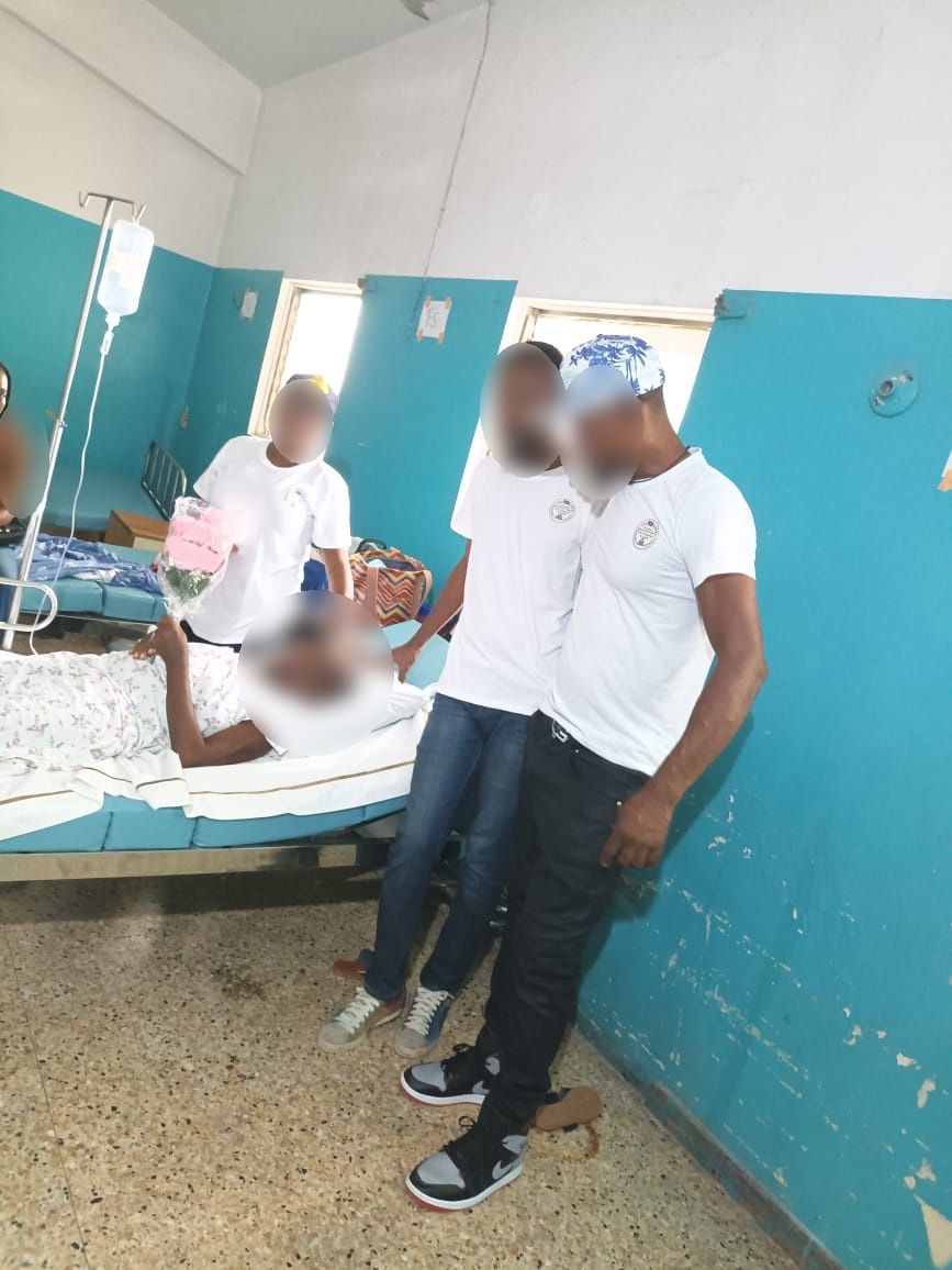 Membres de l'association au chevet d'une patiente hospitalisée, une fleur à la main